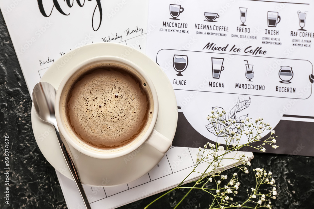 Cup of hot coffee and menu on table in cafe