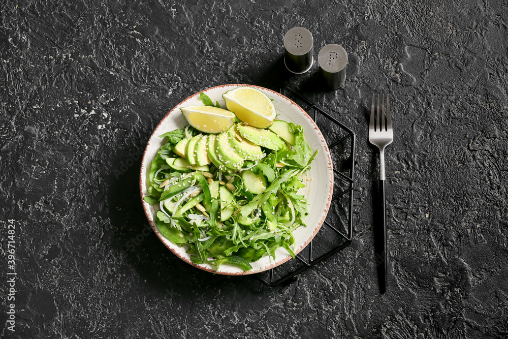 Plate with tasty arugula salad on dark background