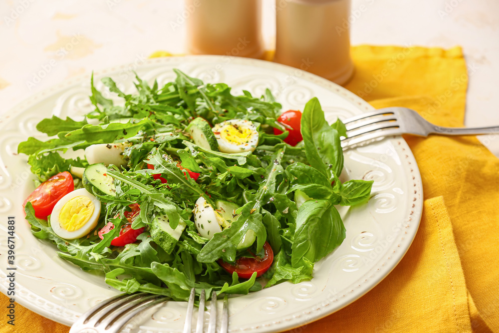 Plate with tasty arugula salad on light table