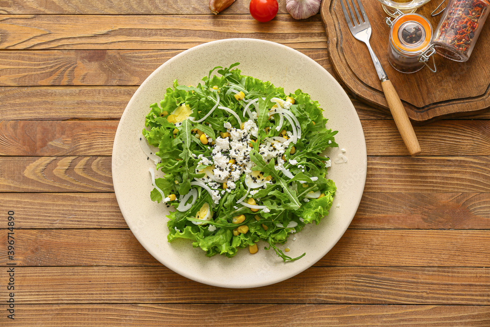 Plate with tasty arugula salad on wooden table