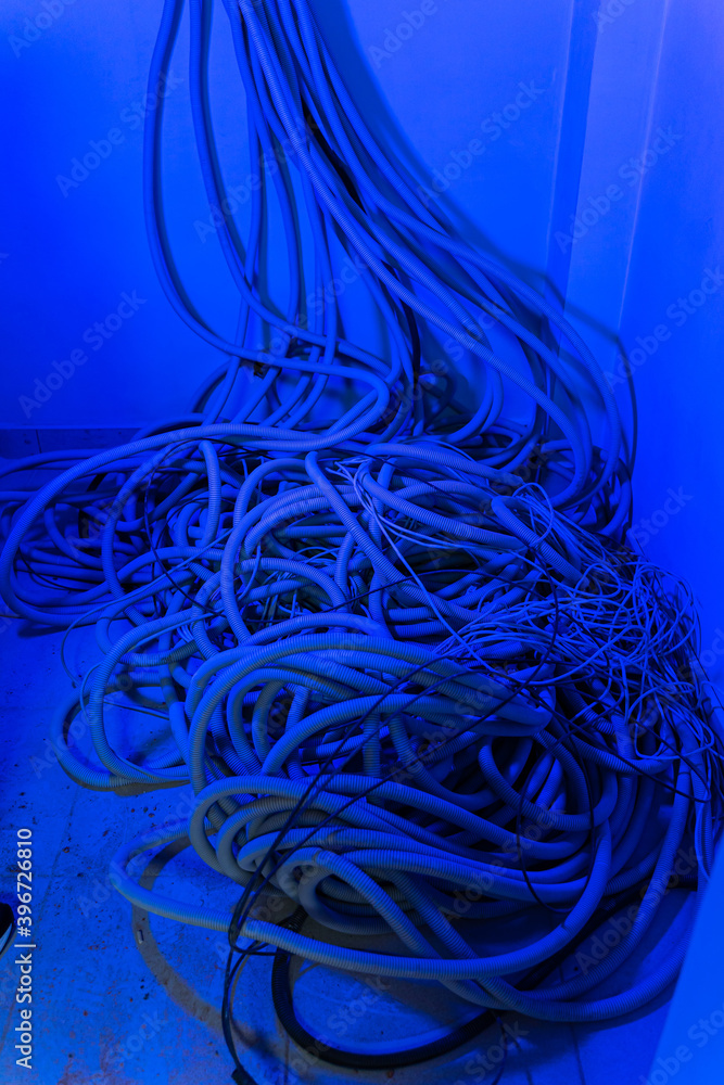 A bundle of communication cables are hanging from the wall in room.