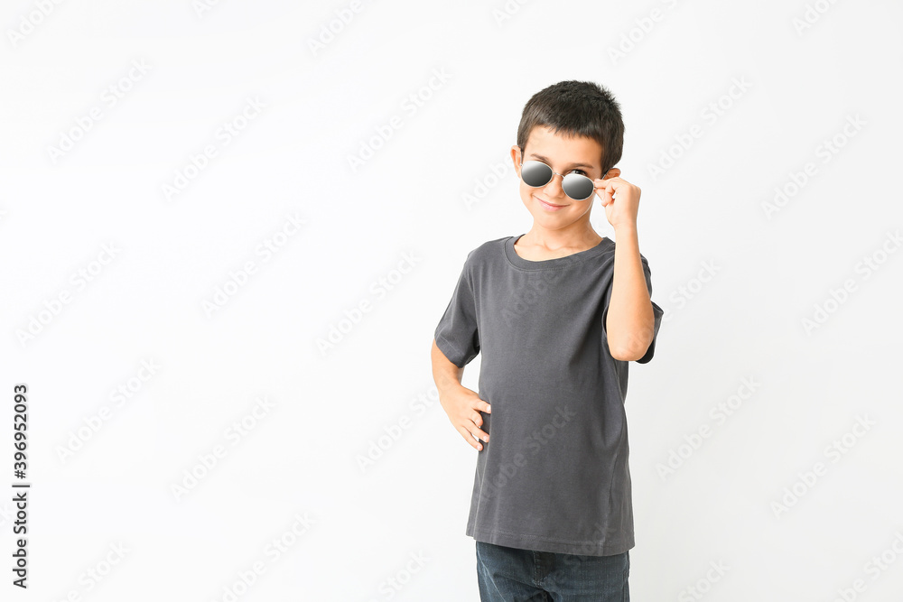 Cute boy wearing stylish sunglasses against white background