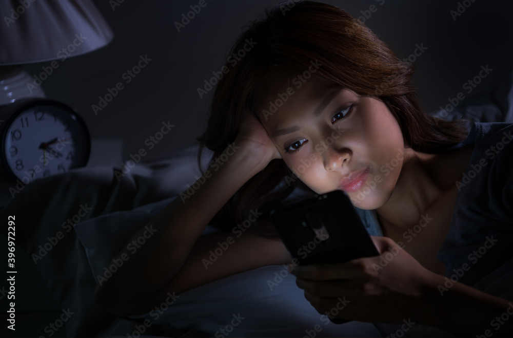 Young woman using a smartphone in her bed at night