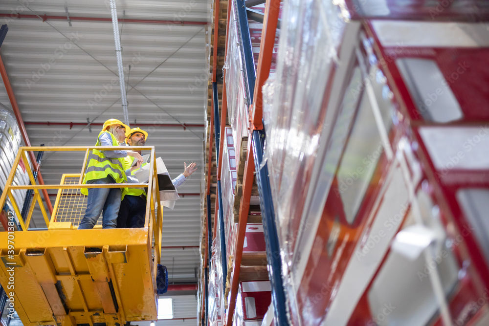 Warehouse workers on lift work platform checking inventory