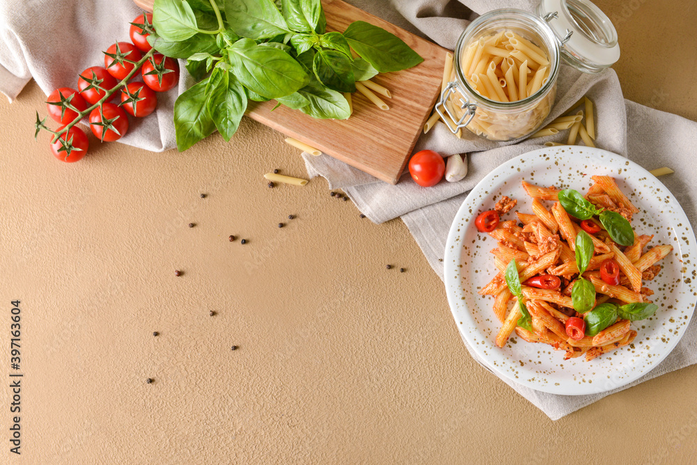 Plate of delicious penne pasta with tomato sauce on color background