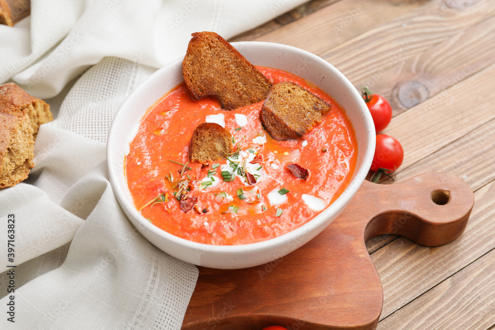 Bowl of tomato cream soup on wooden table