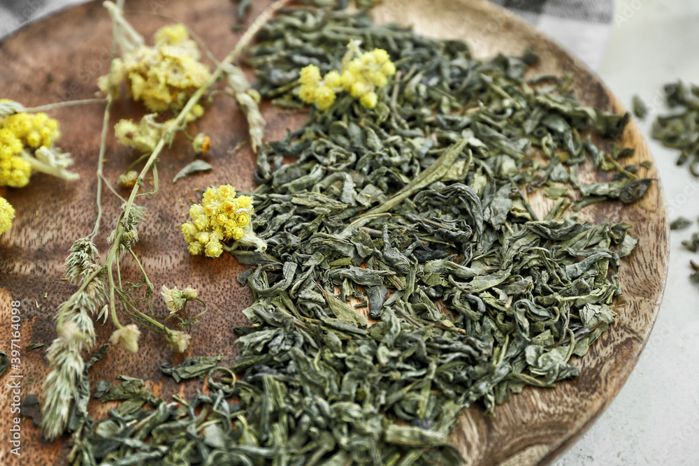 Dry green tea with herbs on wooden plate