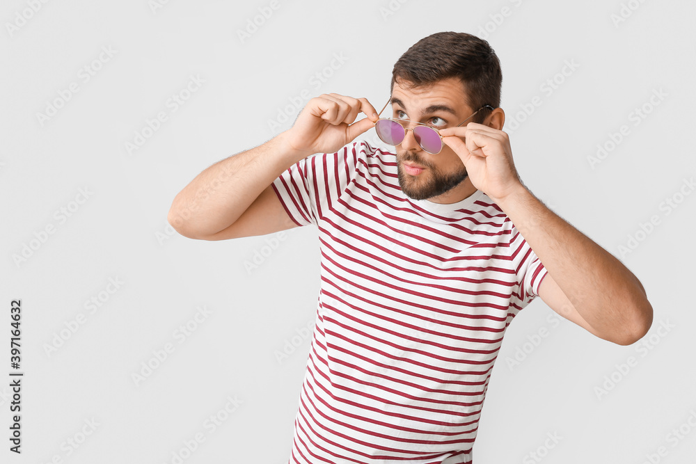 Handsome man with stylish sunglasses on light background