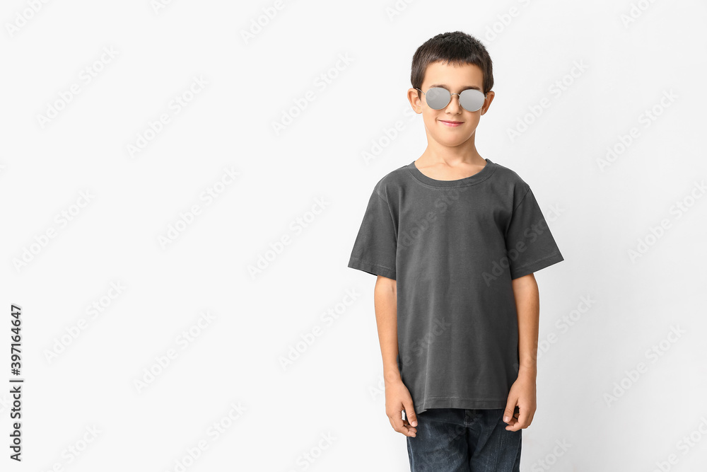 Cute boy wearing stylish sunglasses against white background