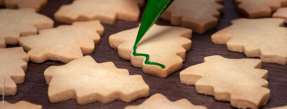 Close up of drawing Christmas tree sugar cookie on wooden table background with icing.