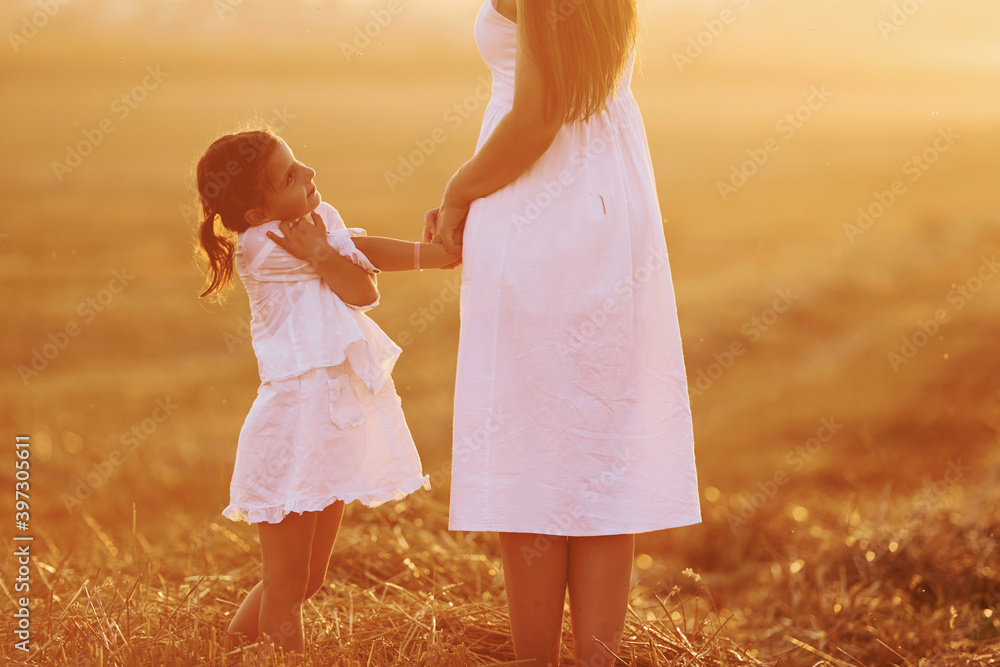 Positive little girl with her mother have weekend outdoors on the summer field together