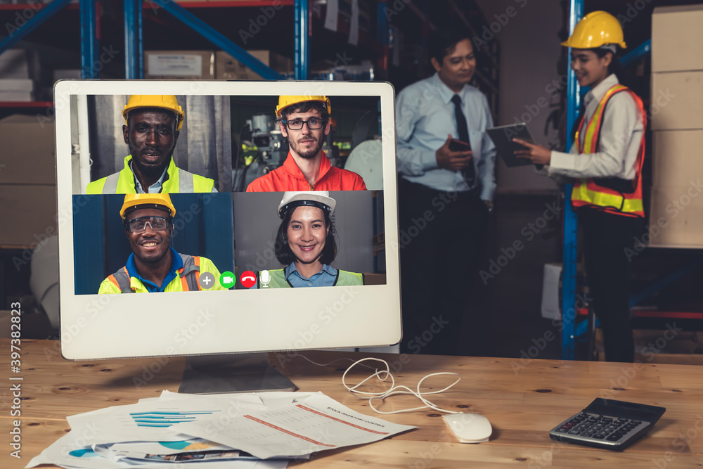 Warehouse staff talking on video call at computer screen in storage warehouse . Online software tech