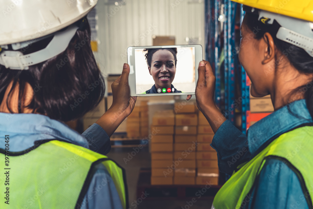 Warehouse staff talking on video call at computer screen in storage warehouse . Online software tech