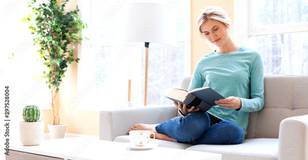 Young woman reading a big book at home