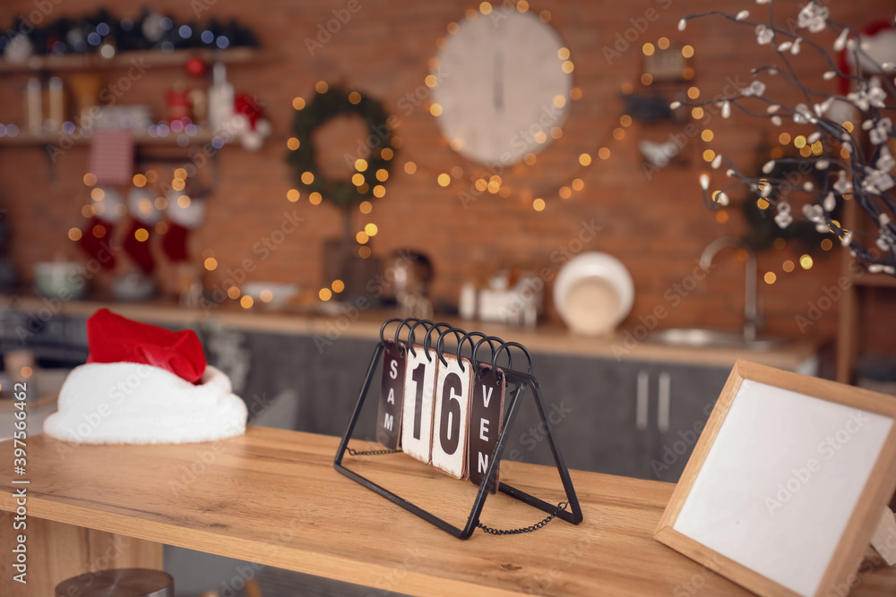 Calendar with Santa hat on shelf in kitchen