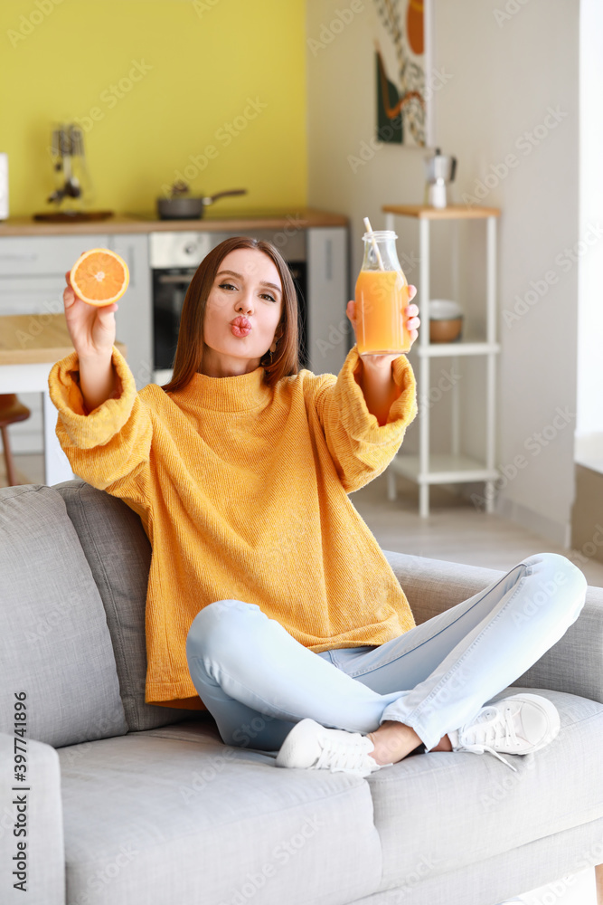 Beautiful young woman drinking orange juice at home