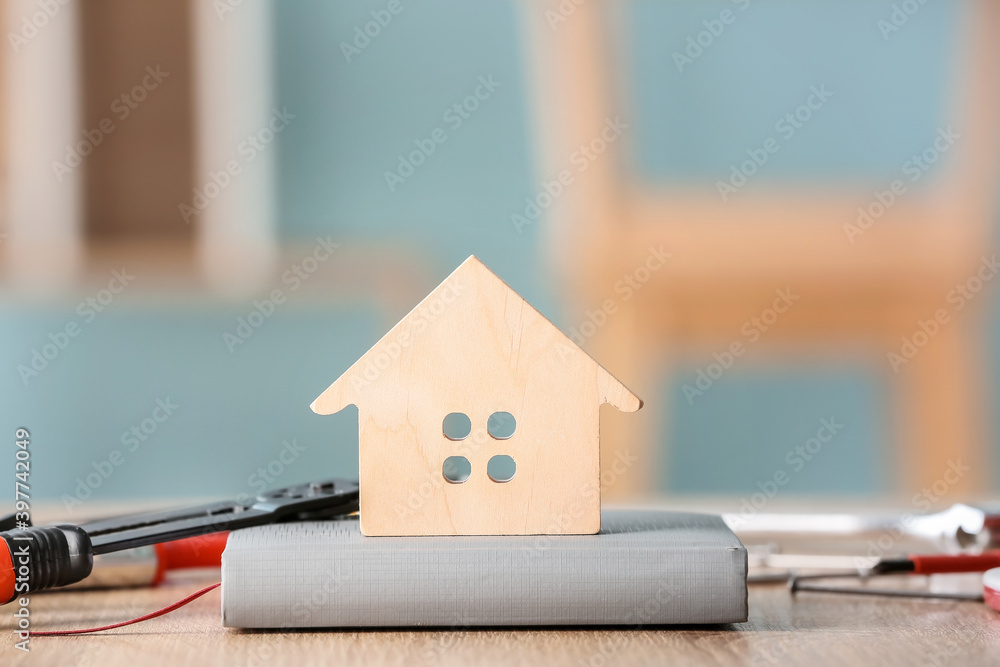 Model of new house with book and supplies on table