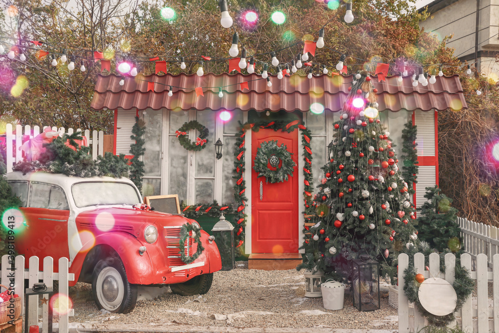 Car and fir tree near house decorated for Christmas