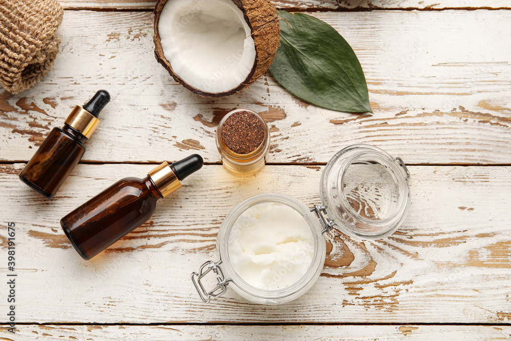 Coconut oil and cosmetics on light wooden background