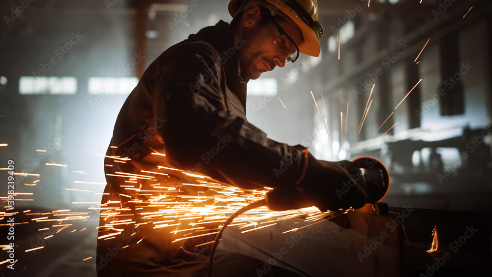 Heavy Industry Engineering Factory Interior with Industrial Worker Using Angle Grinder and Cutting a