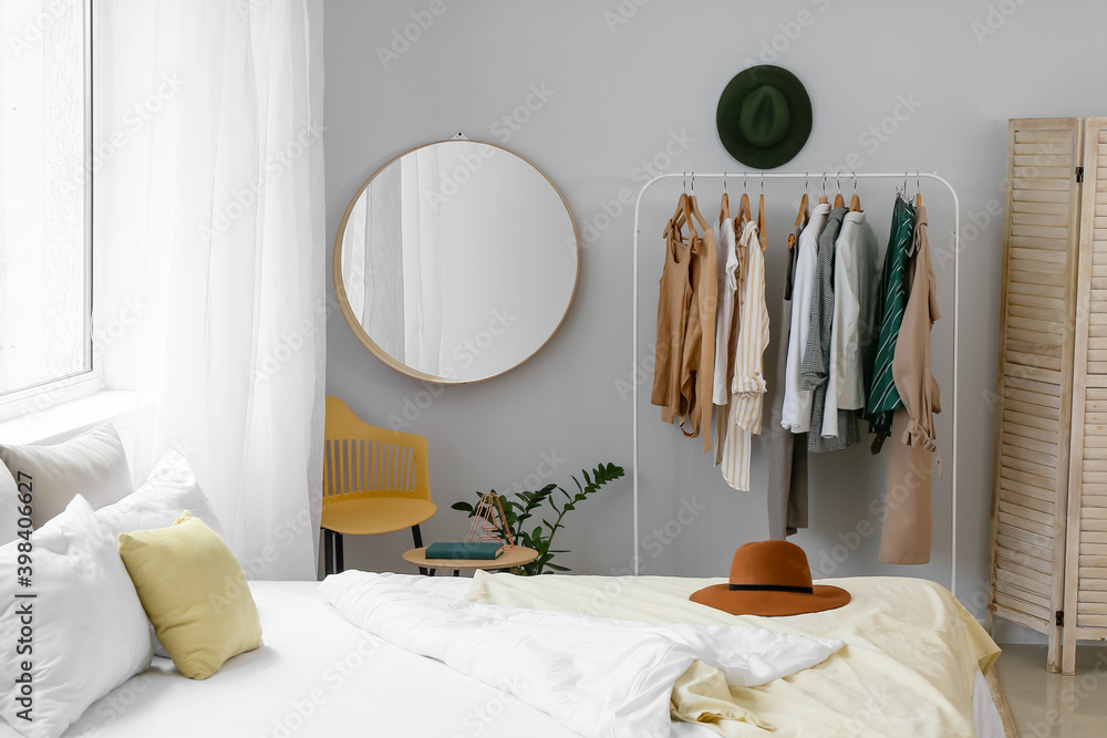 Interior of stylish bedroom with clothes rack