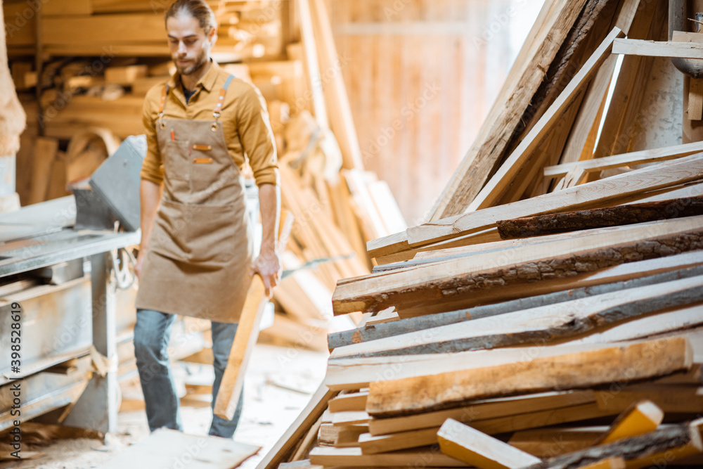 Old wood storage with pile of boards and carpenter on the background at the carpentry