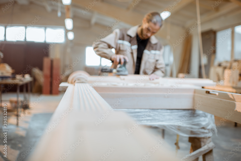 Carpenter grinding joinery product with carvings, finishing woodwork at the carpentry manufacturing