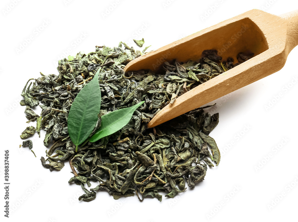 Dry tea leaves and wooden scoop on white background