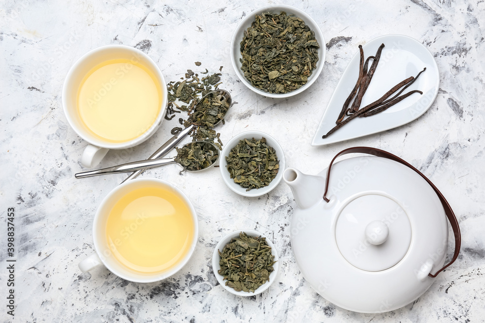 Cups of hot aromatic tea and bowls with dry tea leaves on table