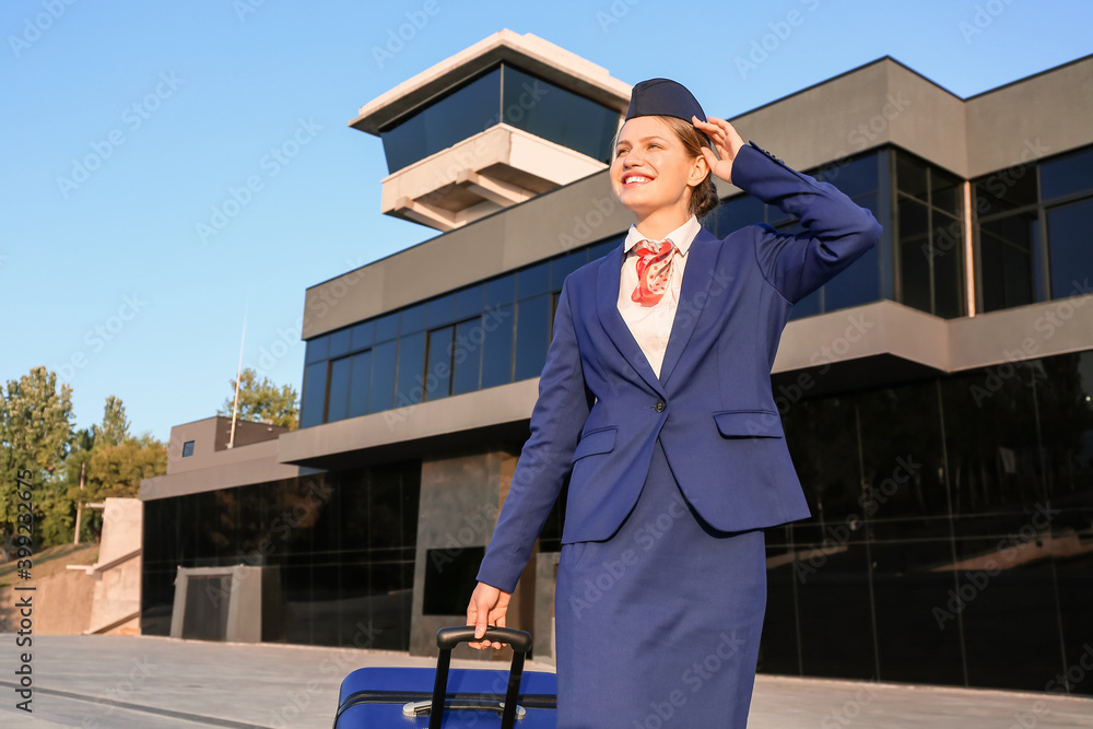 Young stewardess with luggage outdoors