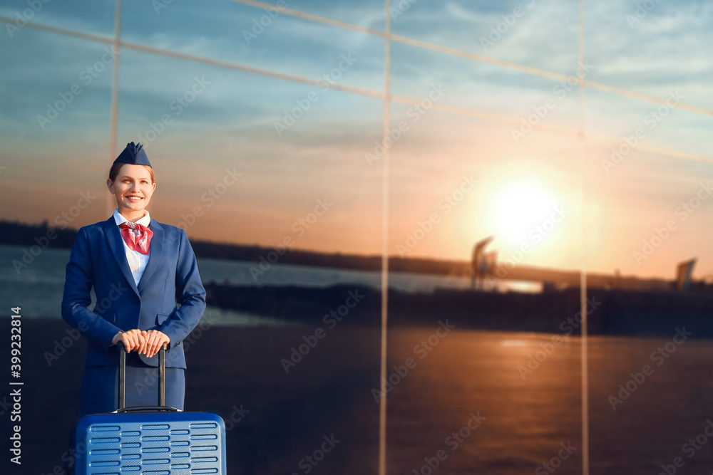 Young stewardess with luggage outdoors