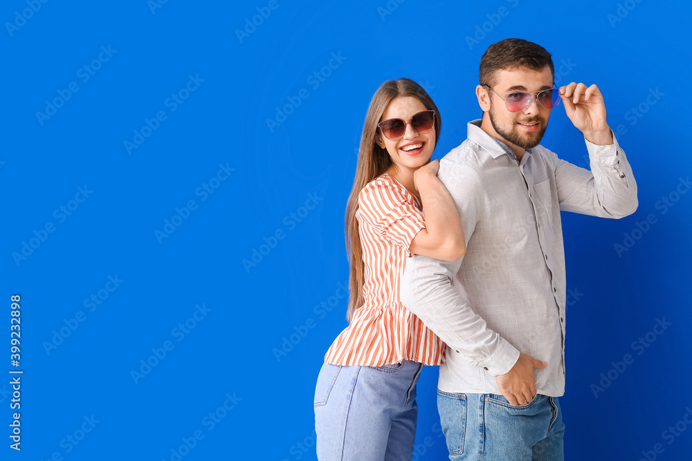 Young couple with stylish sunglasses on color background