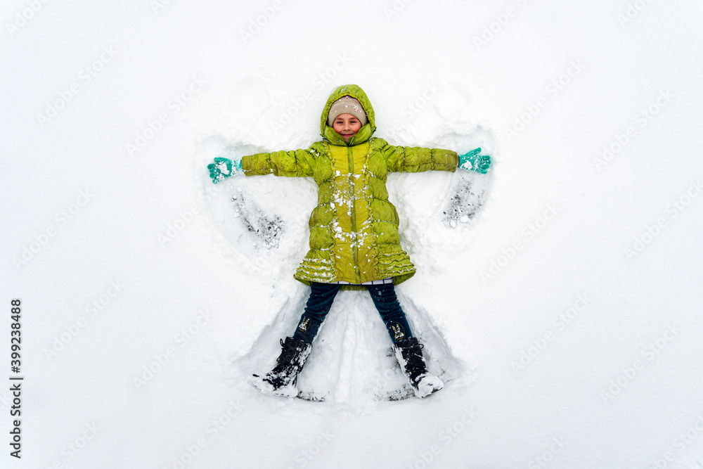 一个穿着绿色夹克的女孩在霜冻的天气里在雪地里玩耍。俯视图。小天使。B