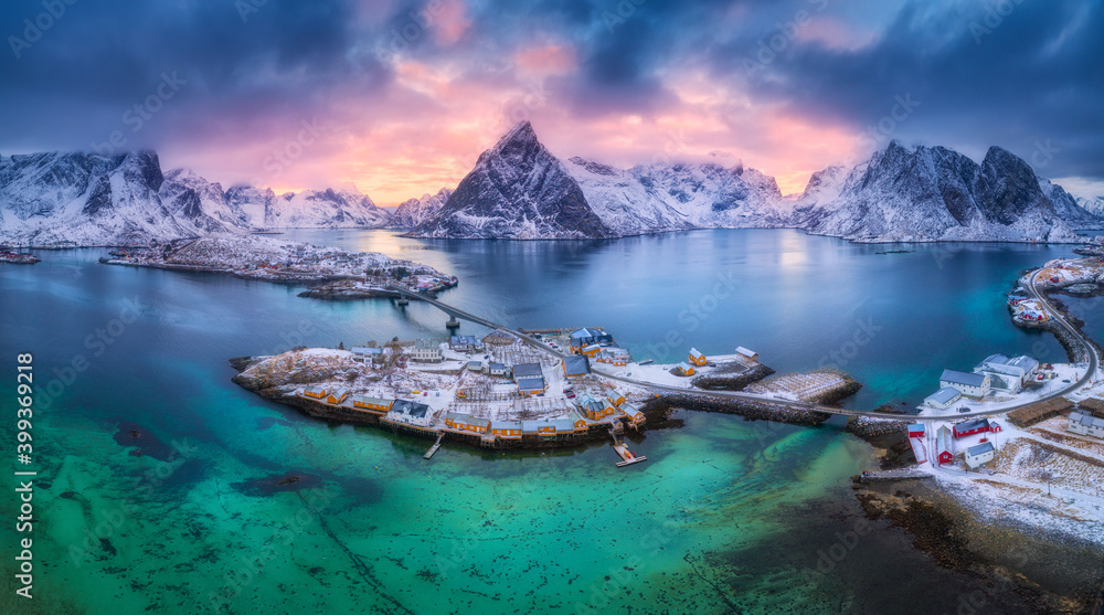 Aerial view of blue sea, snowy mountains, rocks, village, buildings, rorbu, road, bridge, colorful c