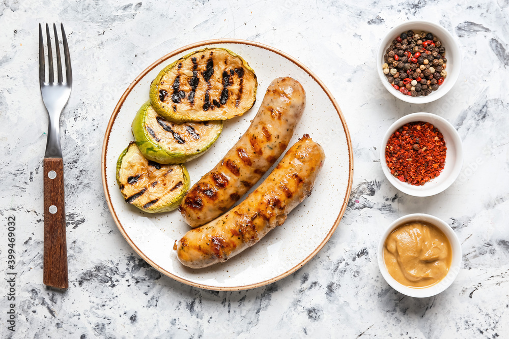 Plate with delicious grilled sausages, vegetables and spices on table