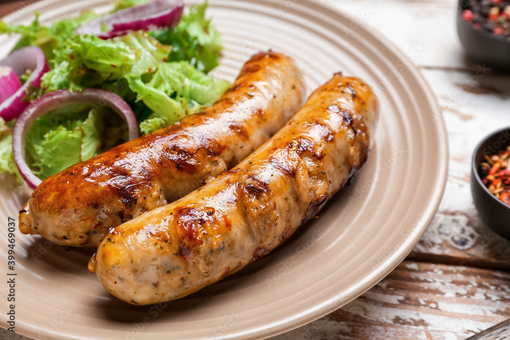 Plate with delicious grilled sausages on wooden table, closeup