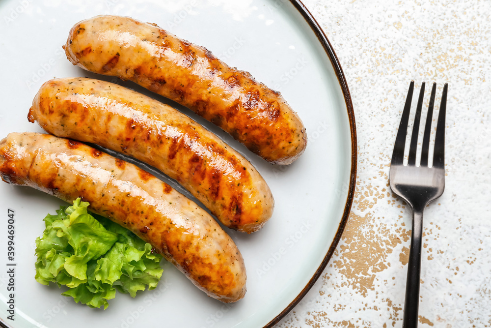 Plate with delicious grilled sausages on wooden table, closeup