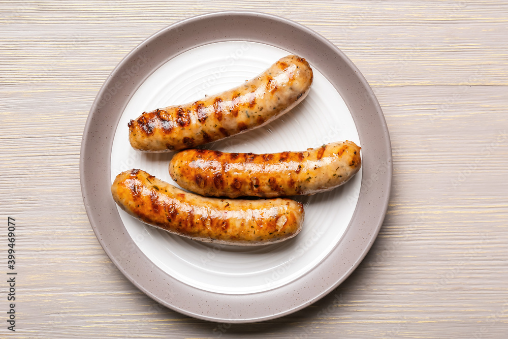 Plate with delicious grilled sausages and vegetables on table