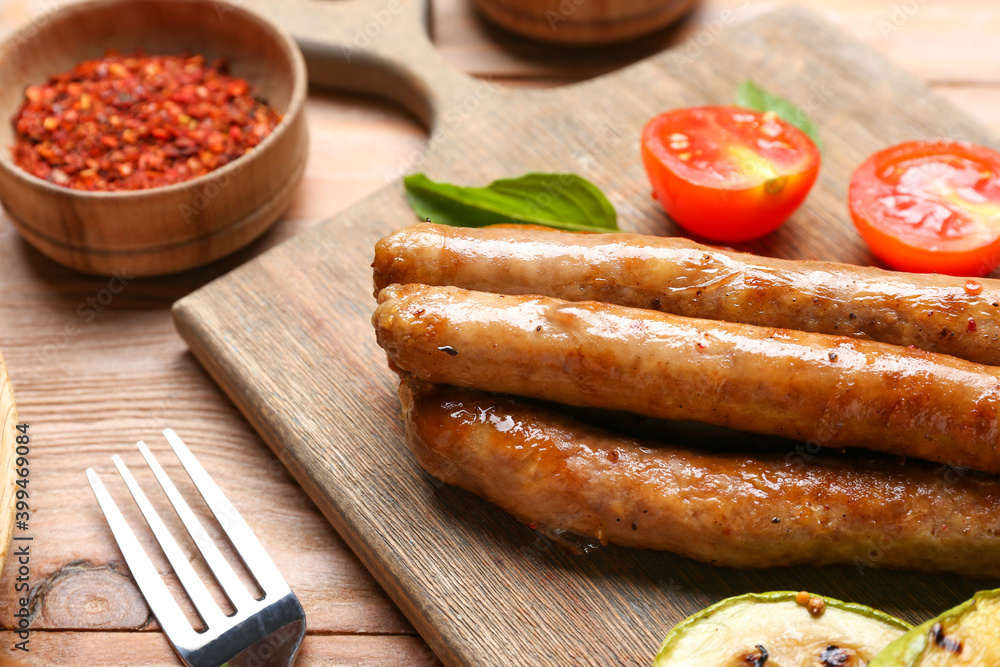 Wooden board with delicious grilled sausages and vegetables, closeup