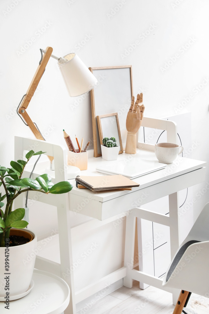 Wooden hand with laptop and lamp on table in interior of room