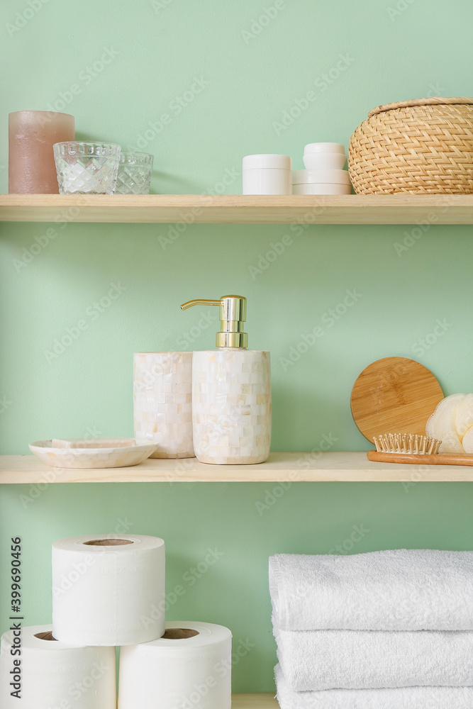 Shelf with bath accessories on color wall