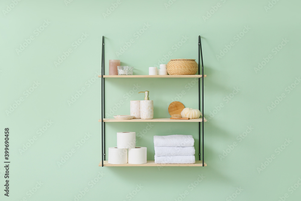 Shelf with bath accessories on color wall