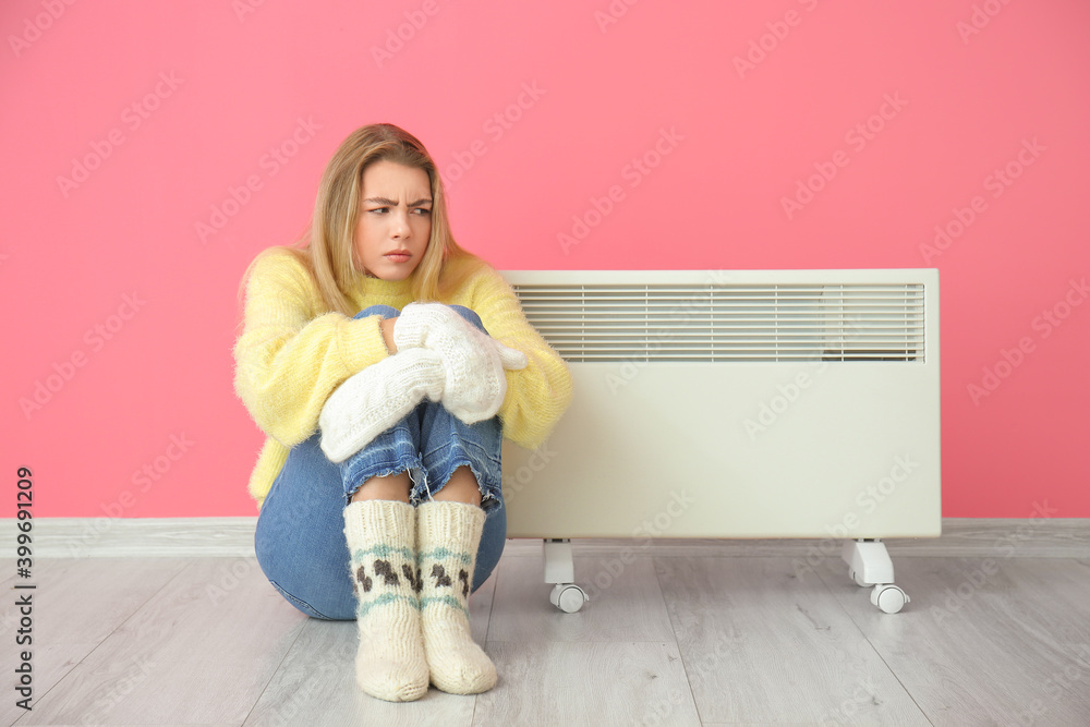 Young woman near electric heater. Concept of heating season