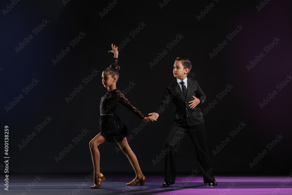 Cute little children dancing against dark background