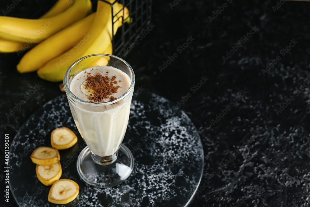 Glass of tasty banana smoothie on dark background