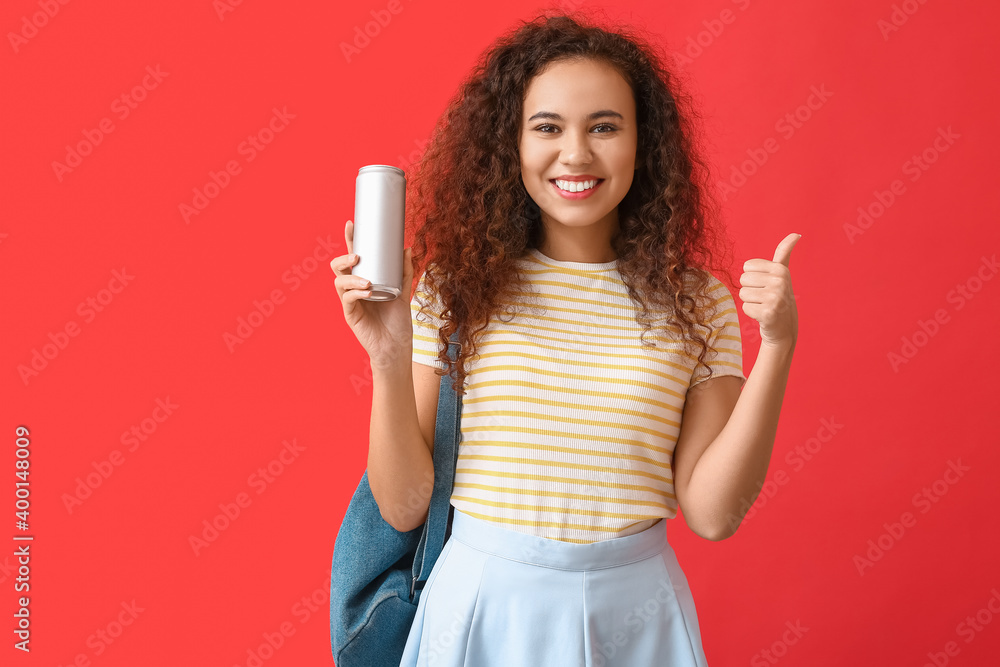 漂亮的非裔美国女人，拿着苏打水，在彩色背景上竖起大拇指