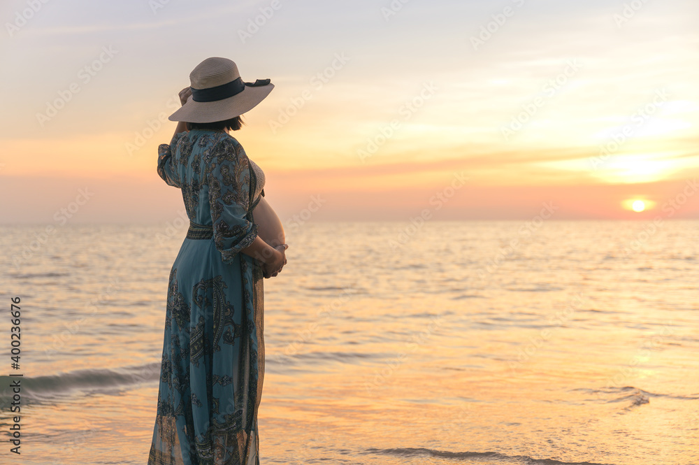 Portrait of Young Asian pregnant woman relax at the beach at sunset