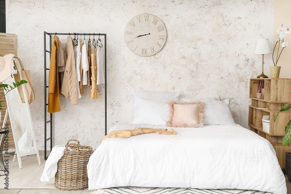 Interior of stylish bedroom with clothes rack