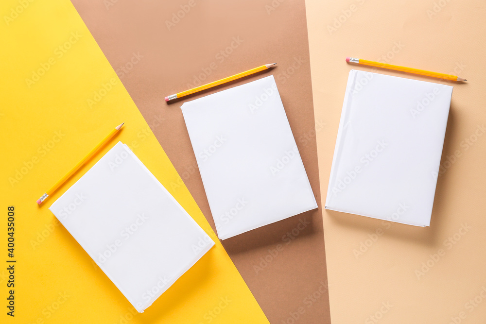 Blank books and pencils on color background