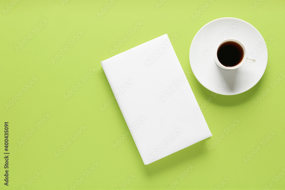 Blank book and cup of coffee on color background